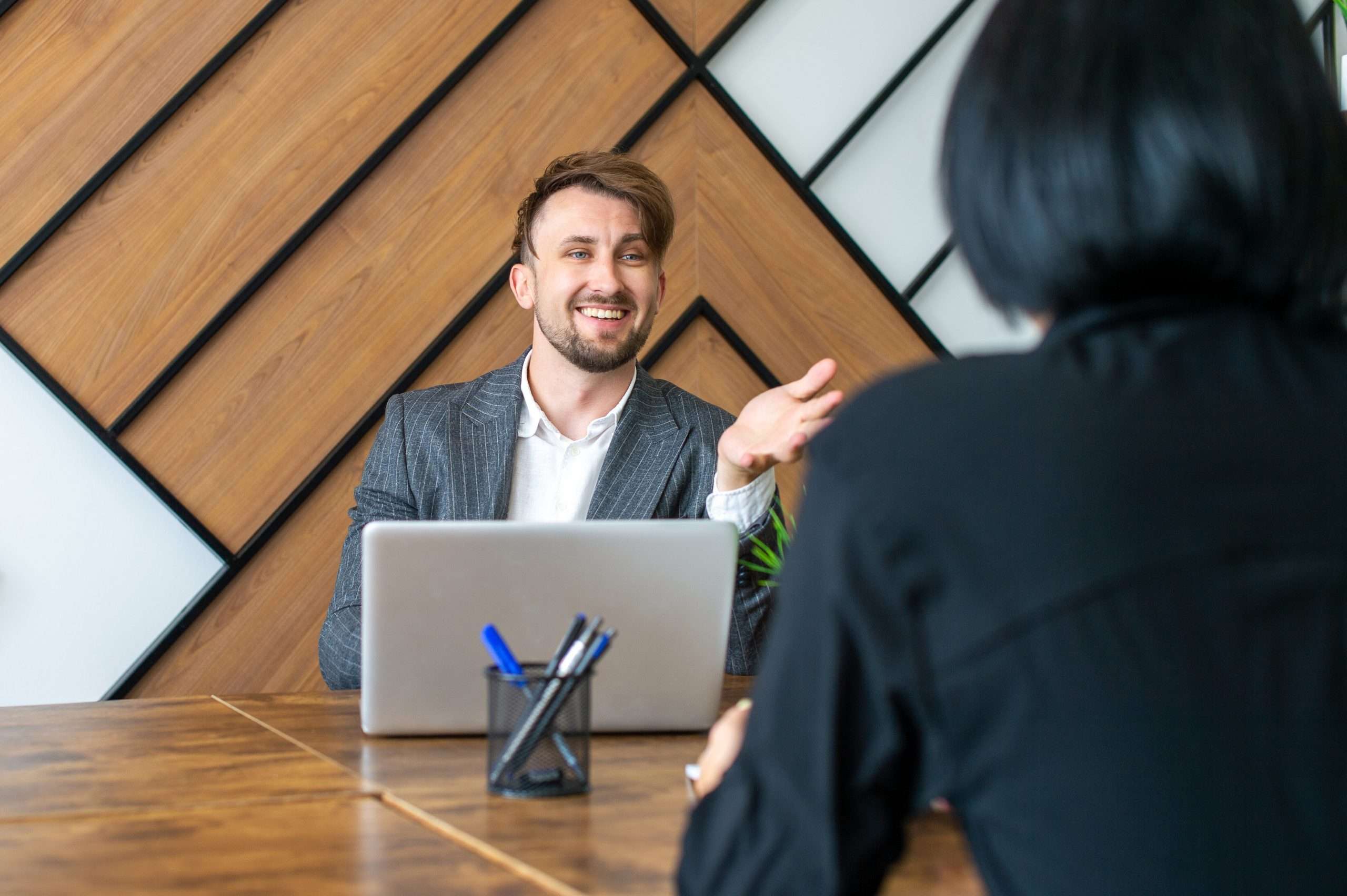 A man in a suit is sitting at his workplace and laughing with colleagues